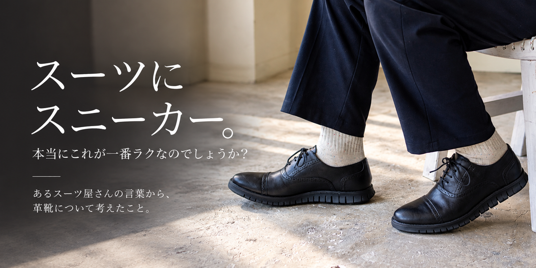 ネイビーのパンツに白いソックスと黒のシューズを合わせ、椅子に腰かけた男性の足元